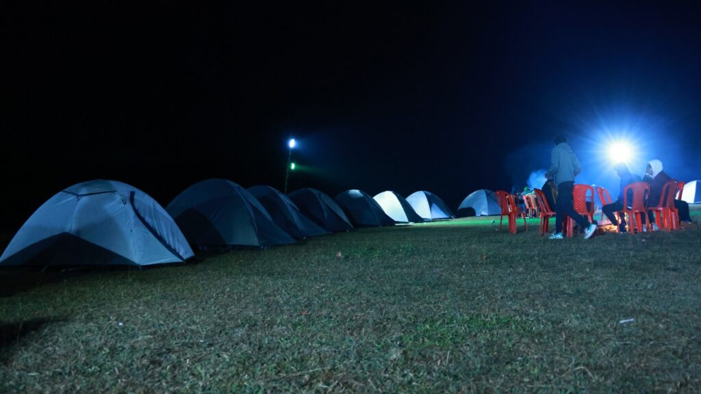 Lit tents at night at a hilltop campsite in Koraput