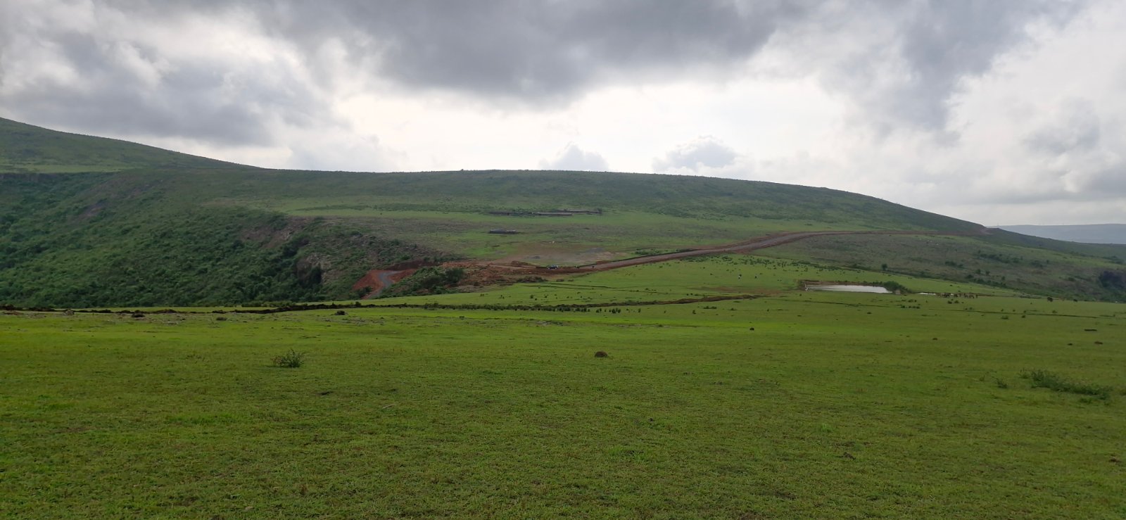 Open green meadow on Kalyamali hilltop in Koraput with the road winding up the hill